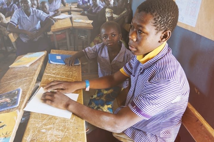 Des écoliers africains en uniforme en train de lire en braille
