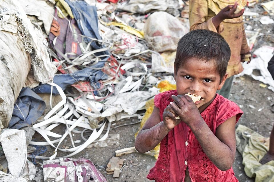 Un enfant dans un bidonville d'Asie mange le peu de nourriture qu'il trouve au milieu des détritus.