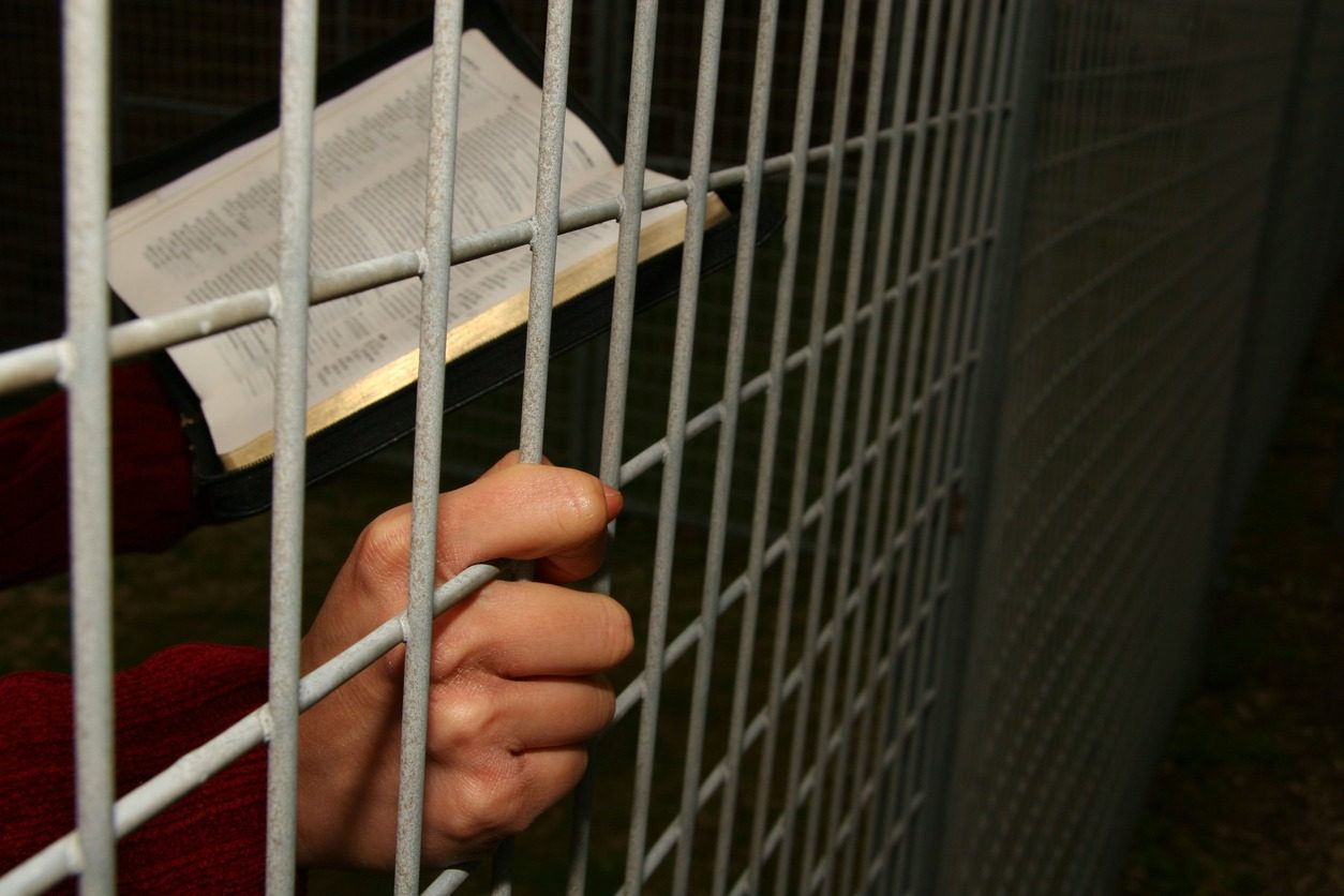 Un prisonnier lit sa Bible à travers les barreaux