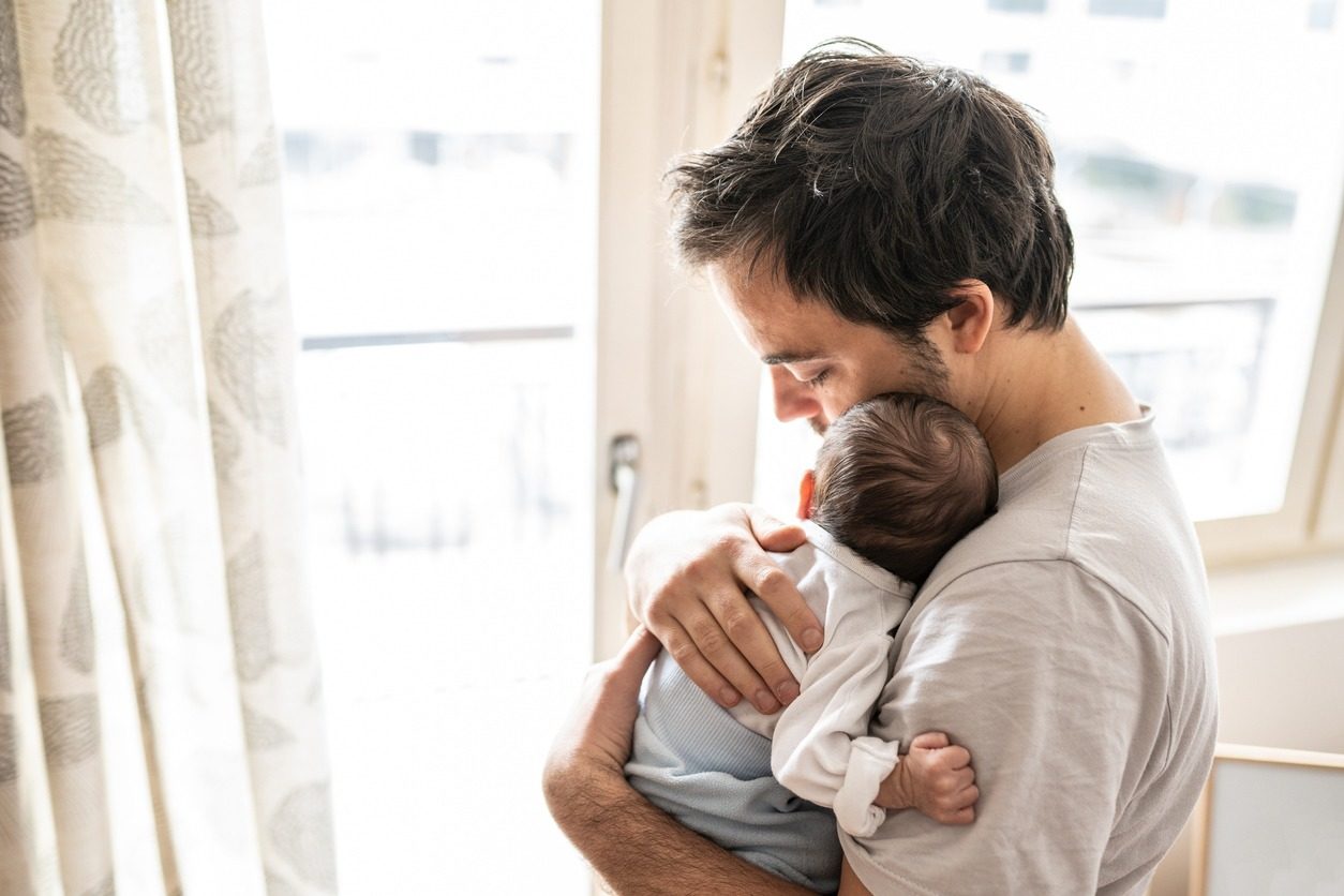 Un jeune papa tient son nouveau né contre lui