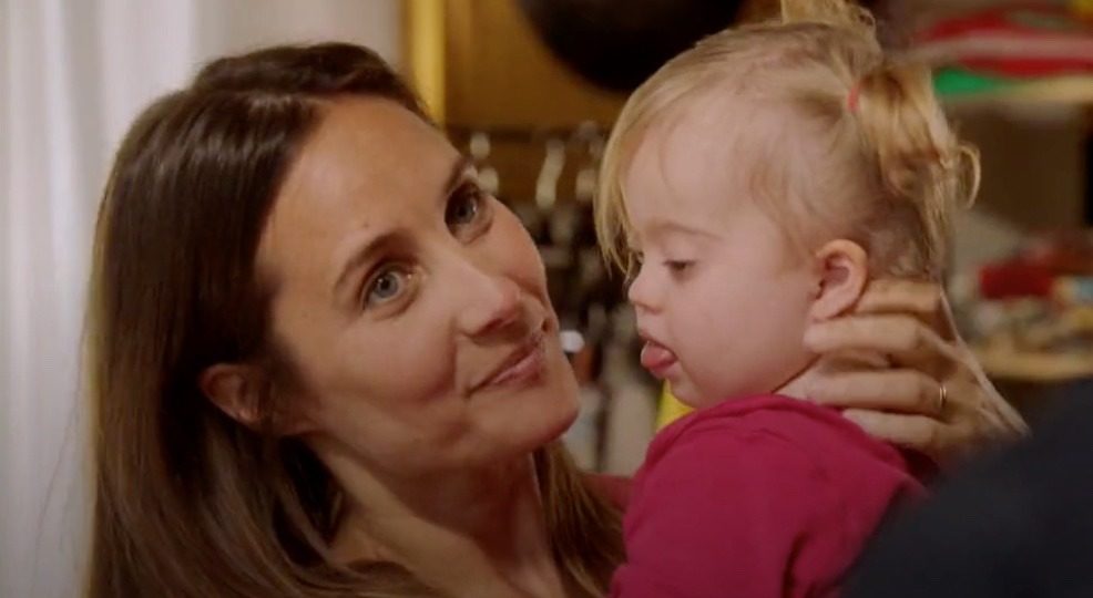 Image d'un téléfilm avec ne mère portant sans ses bras sa petite fille porteuse de trisomie 21