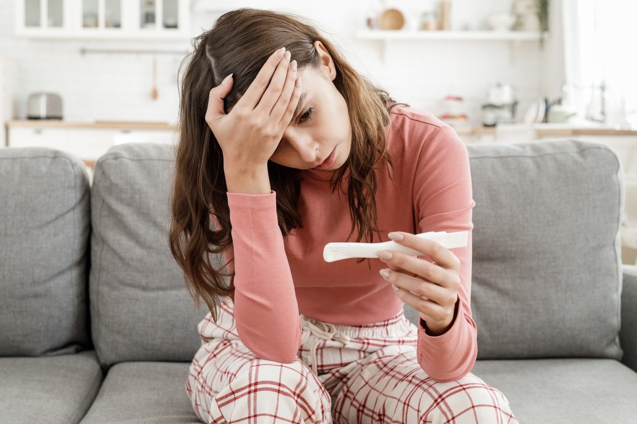 Jeune femme inquiète car elle a obtenu des résultats positifs au test de grossesse, assise seule à la maison