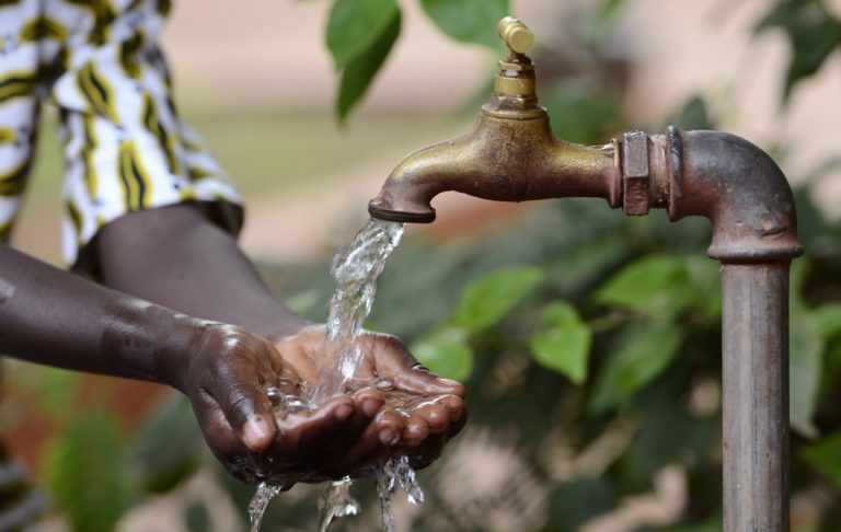 Les mains d'un enfant africain ouvertes en dessous d'un robinet. Photo d'illustration