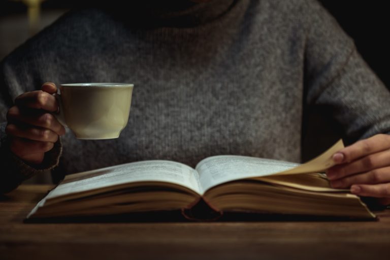 Une femme lisant sa Bible le soir, une tasse à la main