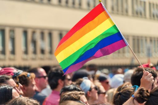 Un drapeau LGBT flotte au vent au-dessus d'une foule en arrière-plan