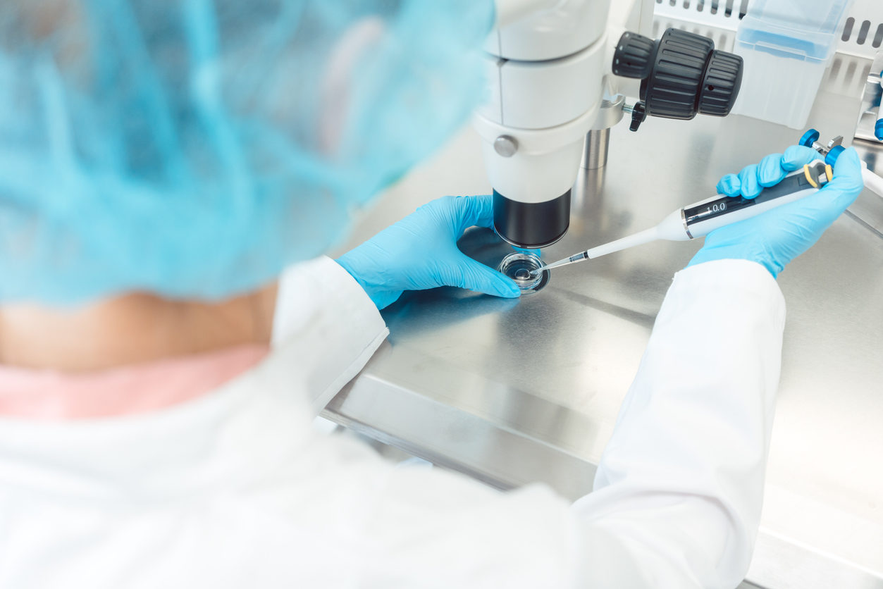 Femme scientifique travaillant au microscope dans un laboratoire, injectant un ovule dans une solution