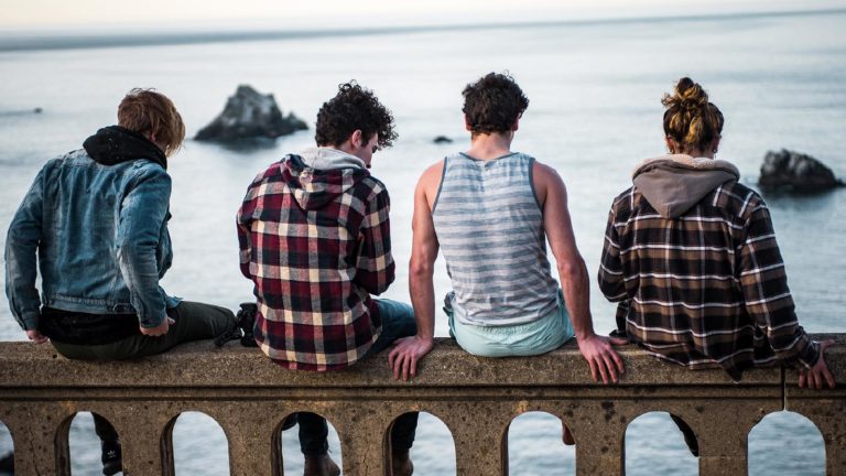 des adolescent assis sur une rambarde en bord de mer