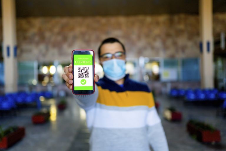 Jeune homme tenant un téléphone avec les détails de sa vaccination contre le covid-19