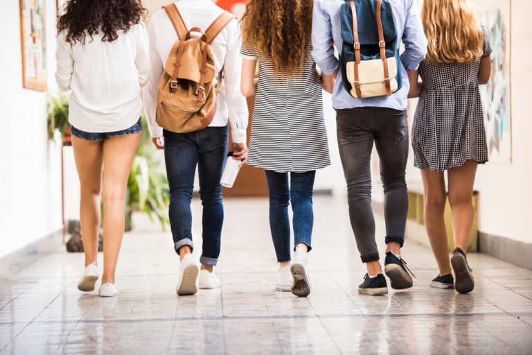 Un groupe d'adolescents, de dos, marchent dans le couloir d'une école.