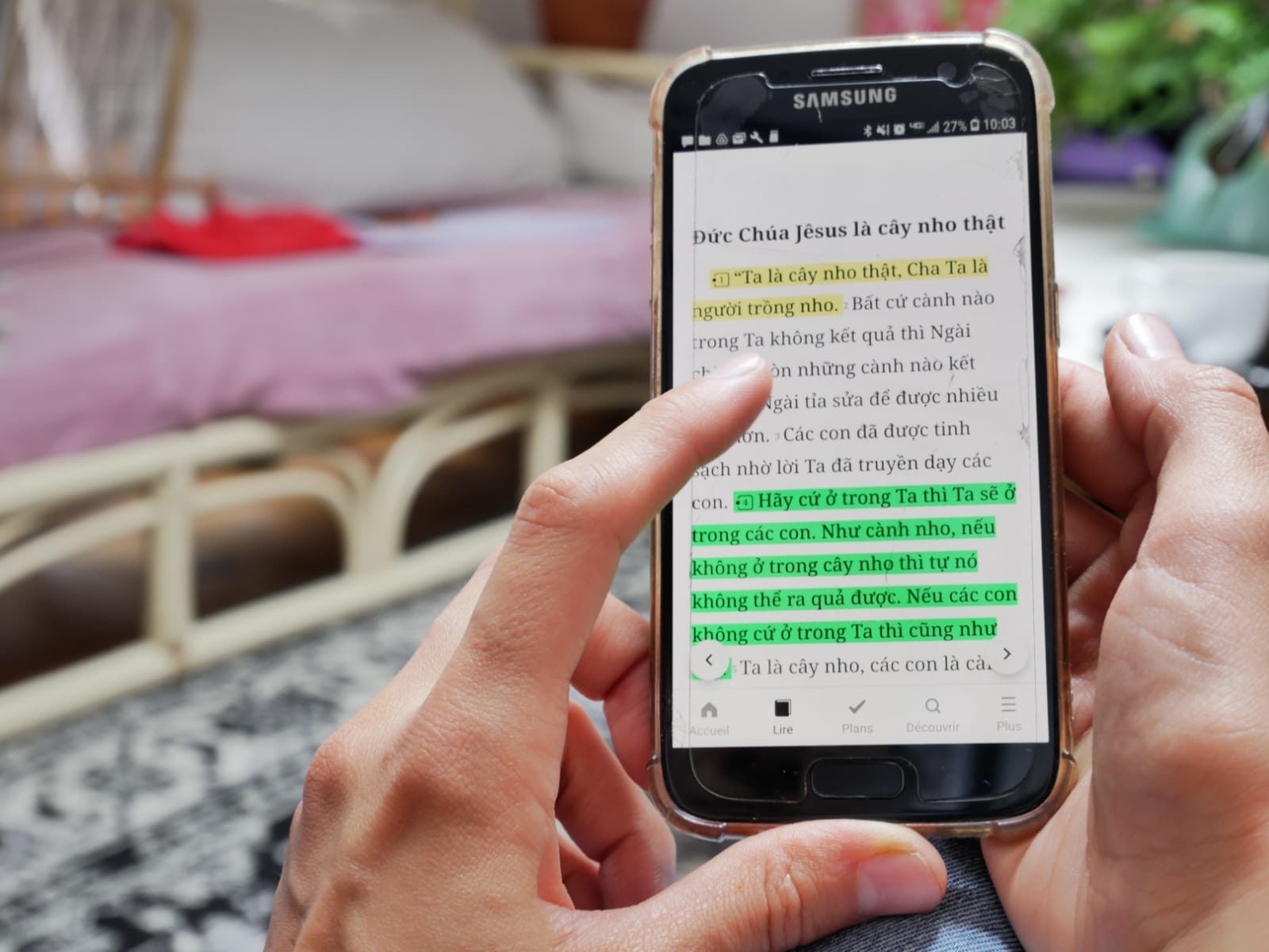 Des mains manipulent un smartphone où figure un texte biblique en langue vietnamienne)