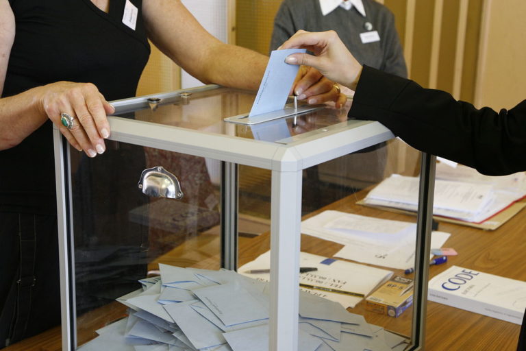 Quelqu'un insère une enveloppe dans une urne lors d'un vote