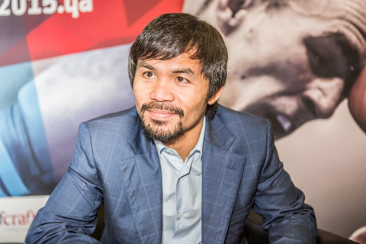 Manny Pacquiao en 2015, en costume et accoudé vers le public après un championnat, souriant