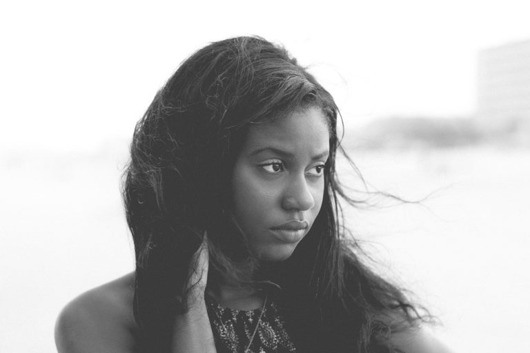Une jeune fille noire aux cheveux longs qui regarde vers sa gauche d'un air préoccupé, photo en noir et blanc