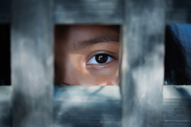 Le regard vide d'un œil d'enfant qui se tient derrière ce qui semble être un cadre en bois