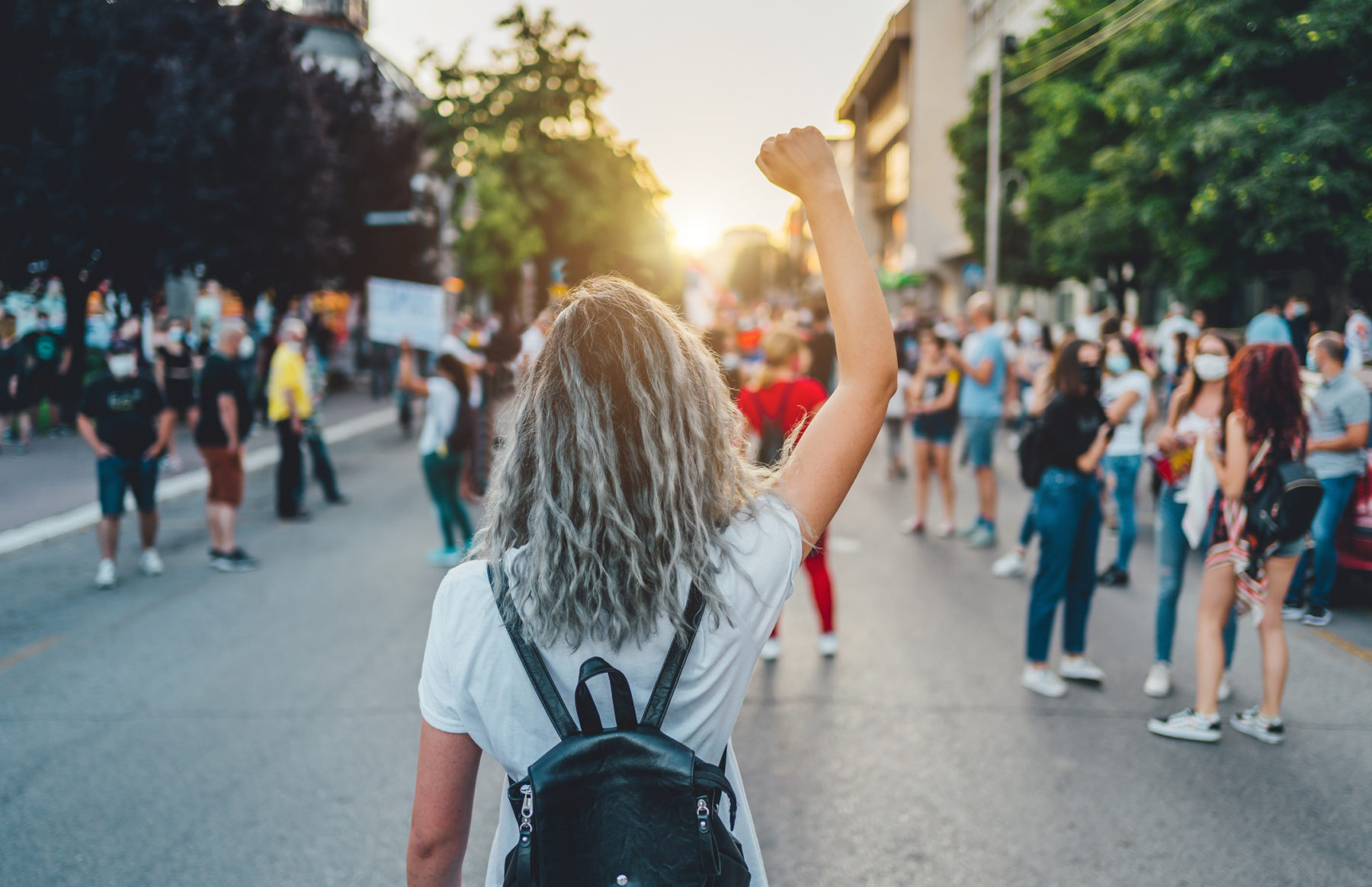 Une manifestation de femme. Au premier plan, une manifestante, de dos, lève le poing vers le ciel