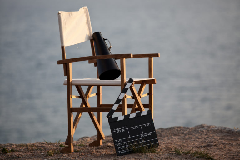 Photo d'un siège de réalisateur ou acteur. A côté se trouve un clap de tournage