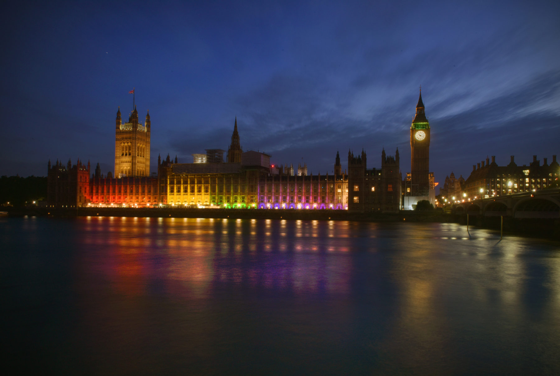 Photo du Parlement du Royaume-Uni à Londres, depuis la Tamise. Il fait nuit et les bâtiments sont illuminés.