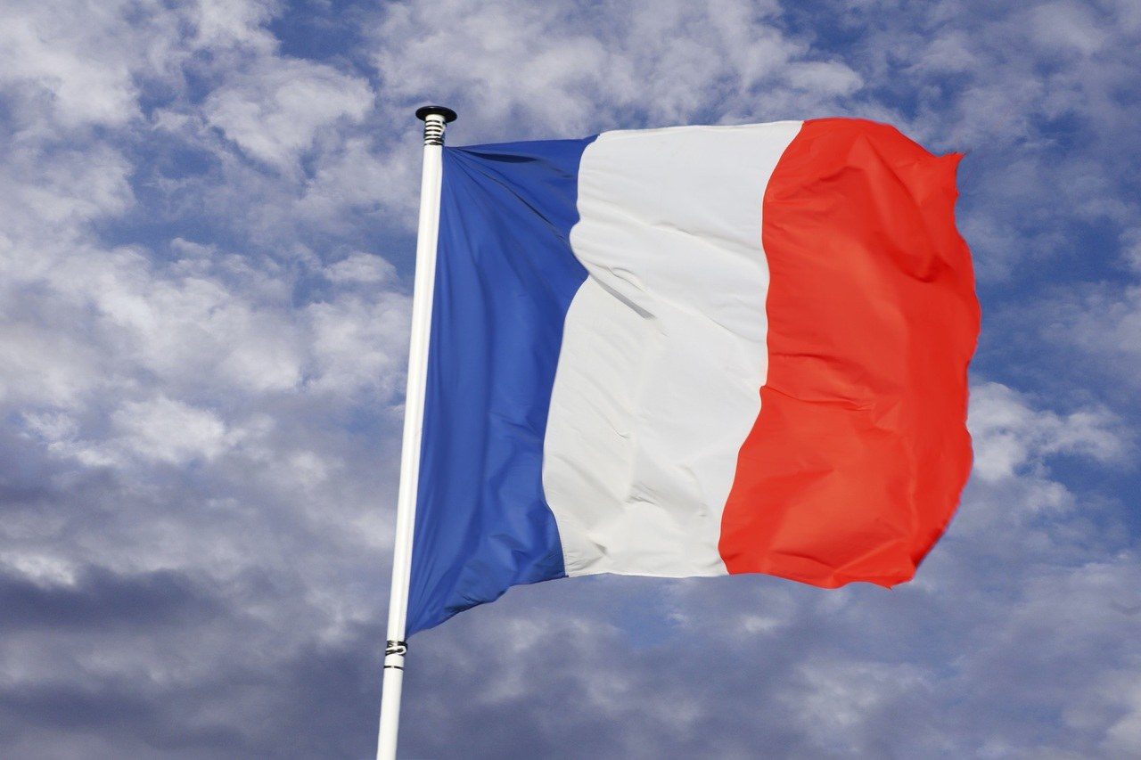 Le drapeau français au vent, sur fond de ciel bleu avec de petits nuages