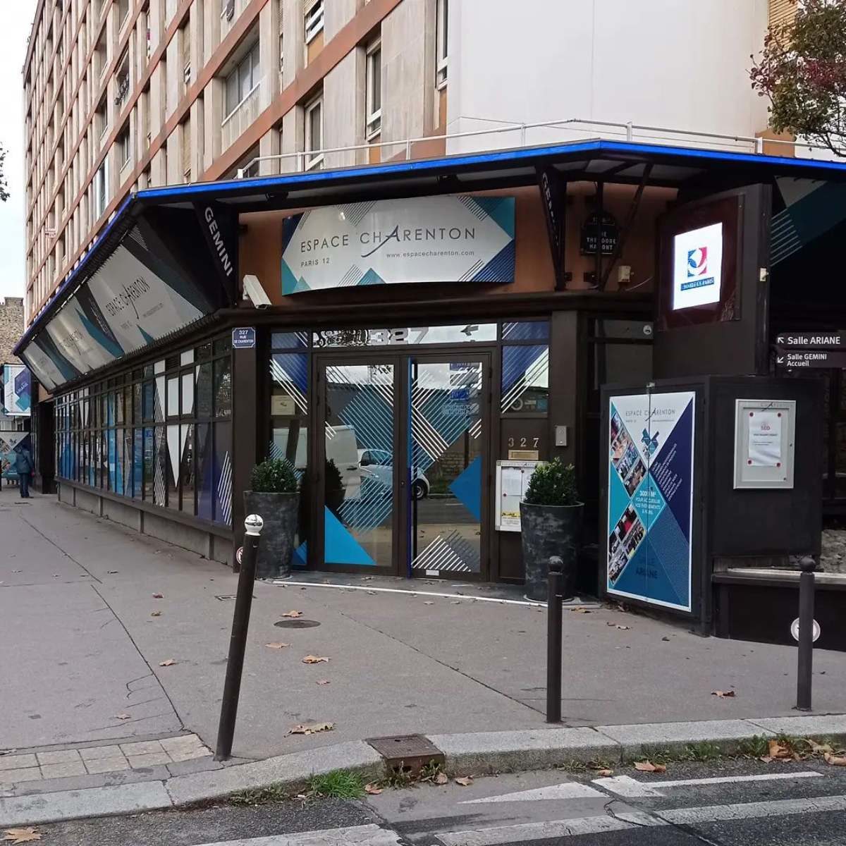 Vue de l'entrée de l'espace Charenton à Paris. C'est un bâtiment de plain pied vitré, aux teintes bleuâtres