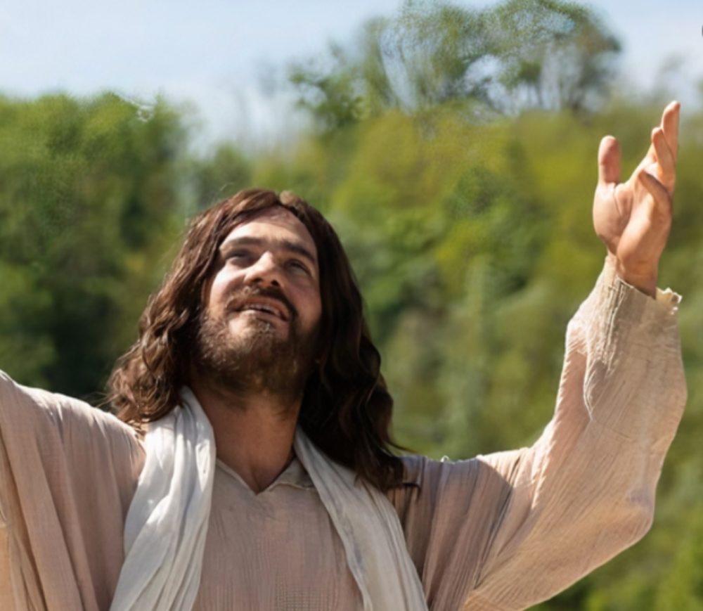 Vincent Villon, alias Jésus, lève les bras et la tête vers le ciel. Il a les cheveux longs et est habillé en vêtement clairs