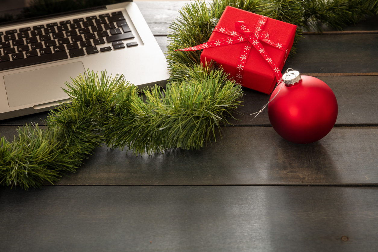 Une guirlande verte, un cadeau rouge et une boule de Noël rouge sont posés près d'un ordinateur