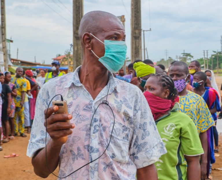 Une file de personnes africaines fait la queue en extérieur. Elles portent des masques anti-covid