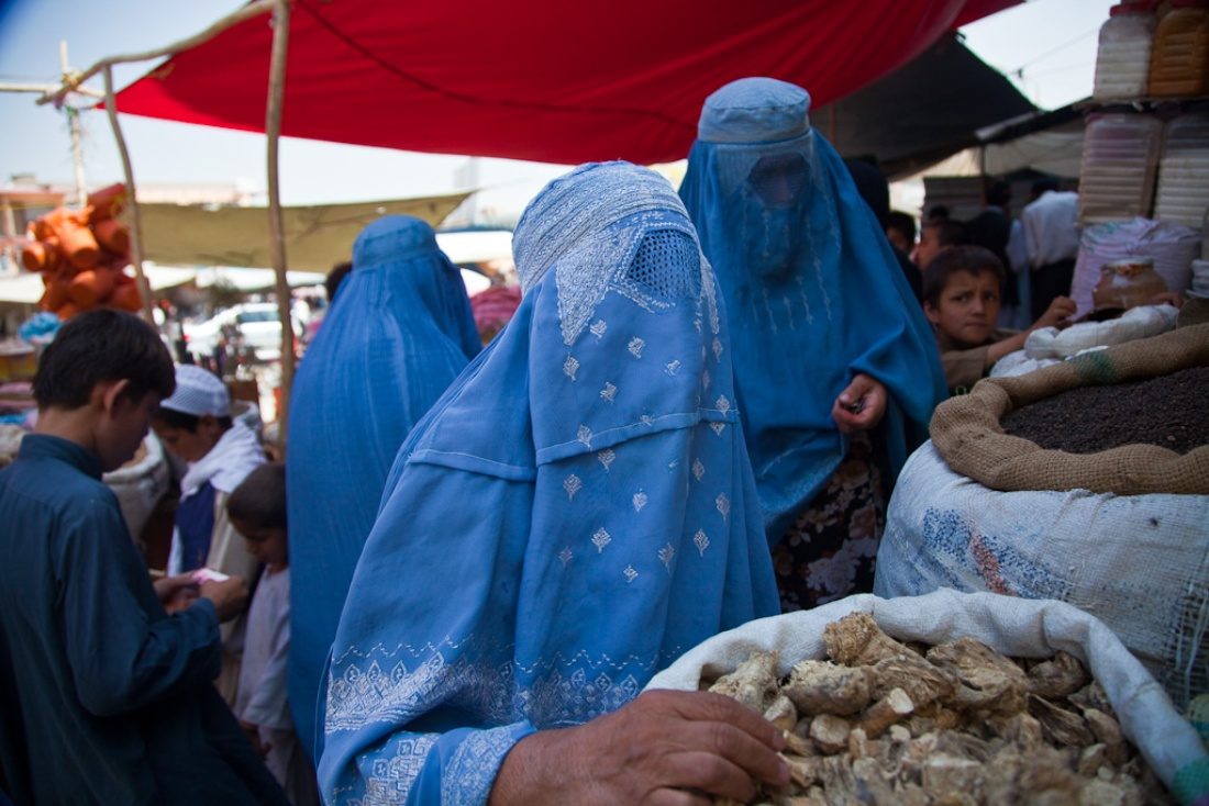 Trois femmes portant des burqas bleues dans un marché