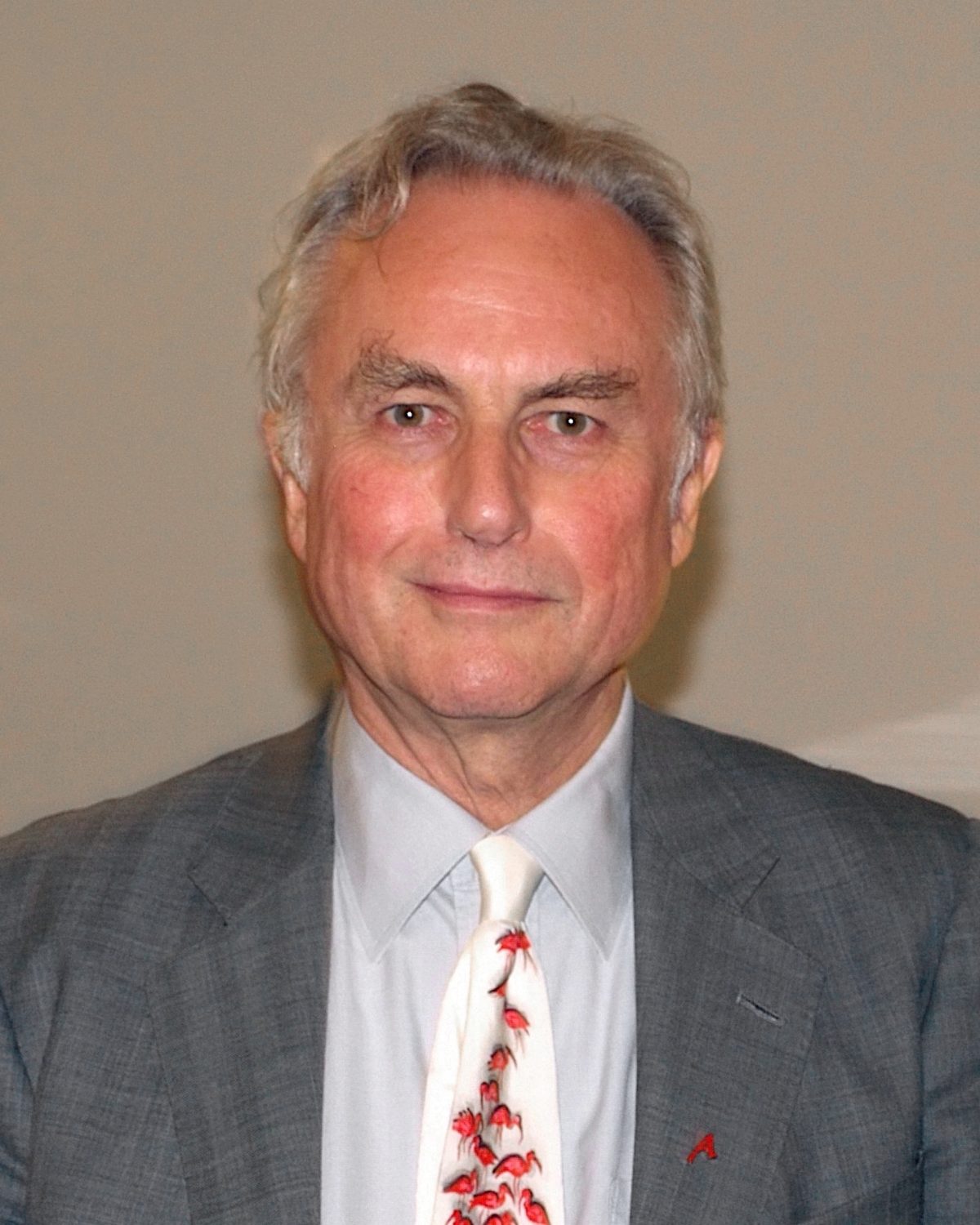 Portrait photo de Richard Dawkins, aux cheveux grisonnant. Il porte un costume gris. Il regarde droit vers l'objectif avec un léger sourire. Sur cette photo, il a environ 70 ans.