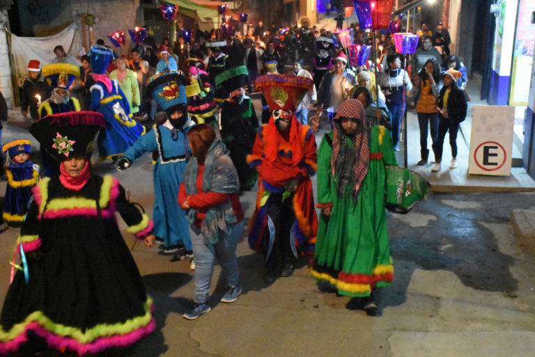 Procession catholique d'une foule multicolore au Mexique. Il fait nuit.