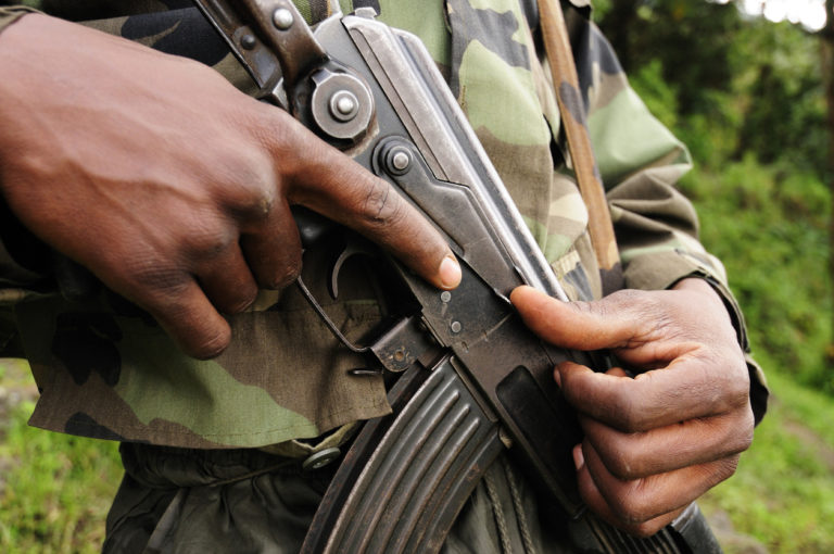 Gros plan sur la main d'un militaire africain qui serre une arme contre lui