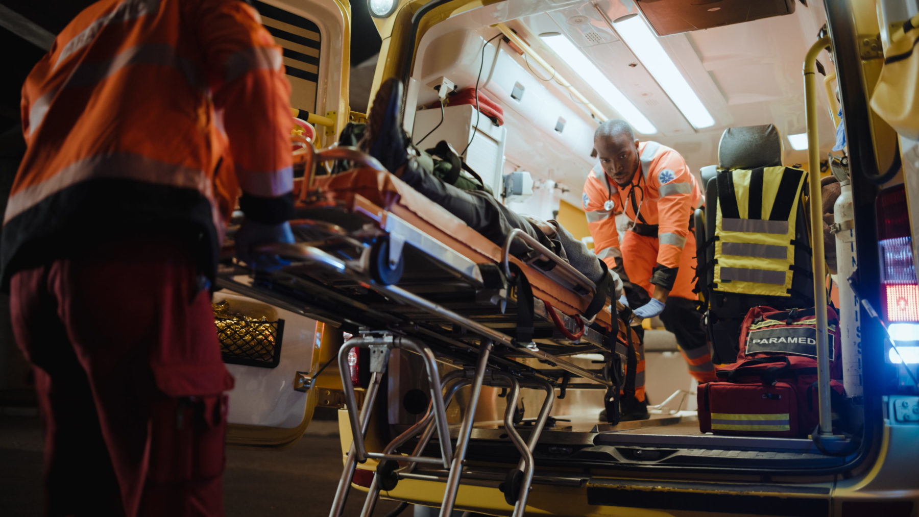 Deux brancardiiers africains font entrer une civière dans une ambulance.