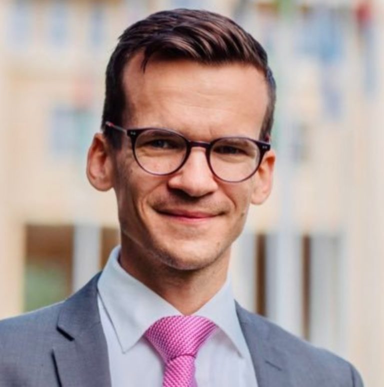 Portrait Photo de Michael Mutzner. Il est jeune, brun et porte des lunettes.