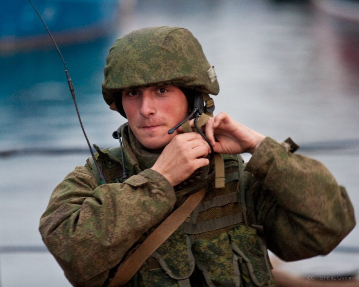 Un militaire russe, regardant vers l'objectif, ajuste la lanière de son casque.