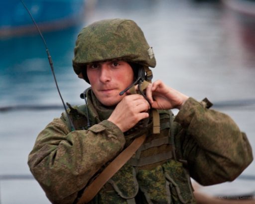 Un militaire russe, regardant vers l'objectif, ajuste la lanière de son casque.