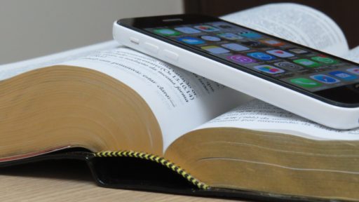 Un smartphone est posé su une Bible ouverte