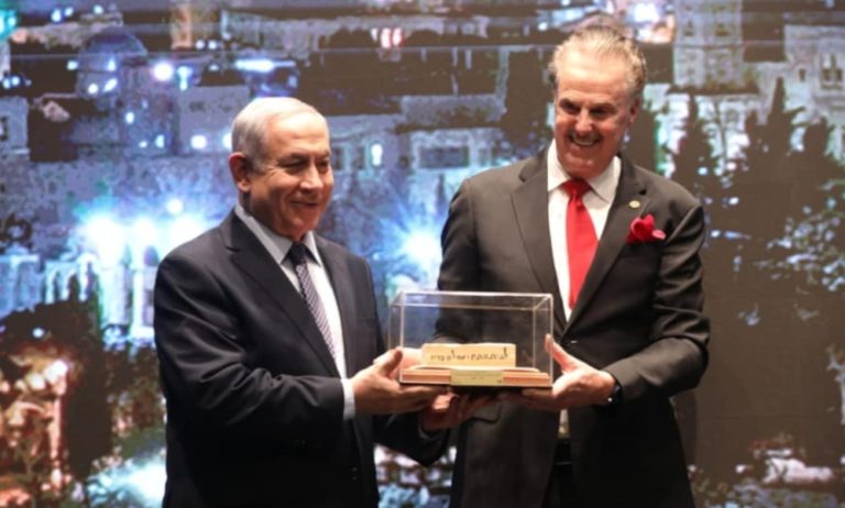 L’ancien premier ministre israélien Benjamin Netanyahu remet une boîte transparente contenant quelques papiers à Mike Evans. Ils sont très souriants. Ils ont tous deux environ 70 ans.
