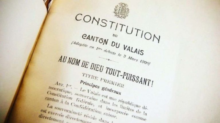 Un livre est ouvert sur la première page de la Constitution du Valais, avec en première mention: "Au nom de Dieu tout-puissant"