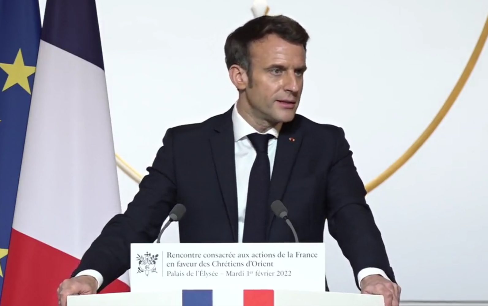 Emmanuel Macron, en costume et cravate noirs, parle, les mains appuyées sur un pupitre. Il a la tête tournée vers la droite. Sur le pupitre se trouvent le drapeau français et un petit écriteau mentionnant: "Rencontre consacrée aux actions de la France en faveur des chrétiens d'Orient".