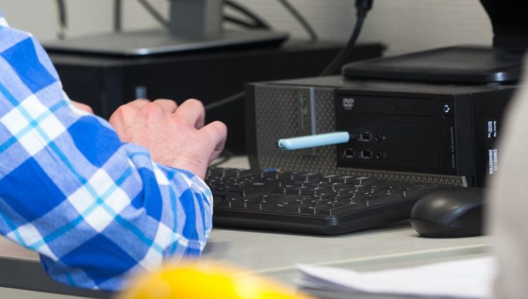 Une partie du bras et la main d'un homme en train de taper sur un clavier d'ordinateur.