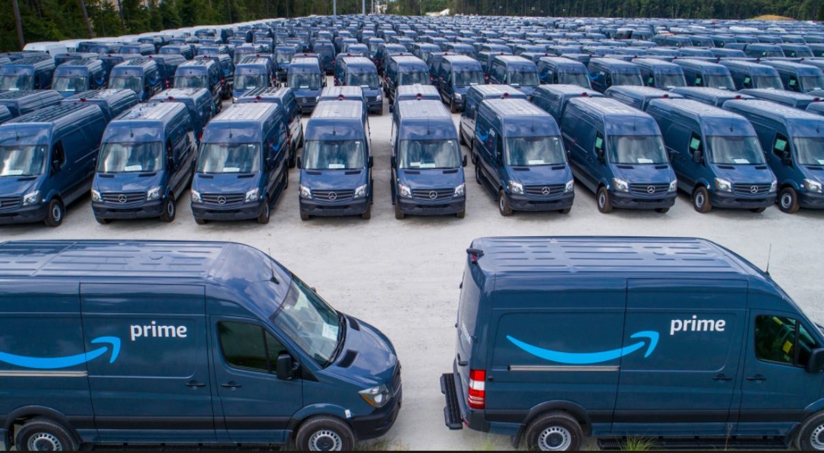 Photo d'un parking où sont alignées des dizaines de camionnettes bleues estampillées Amazon Prime.