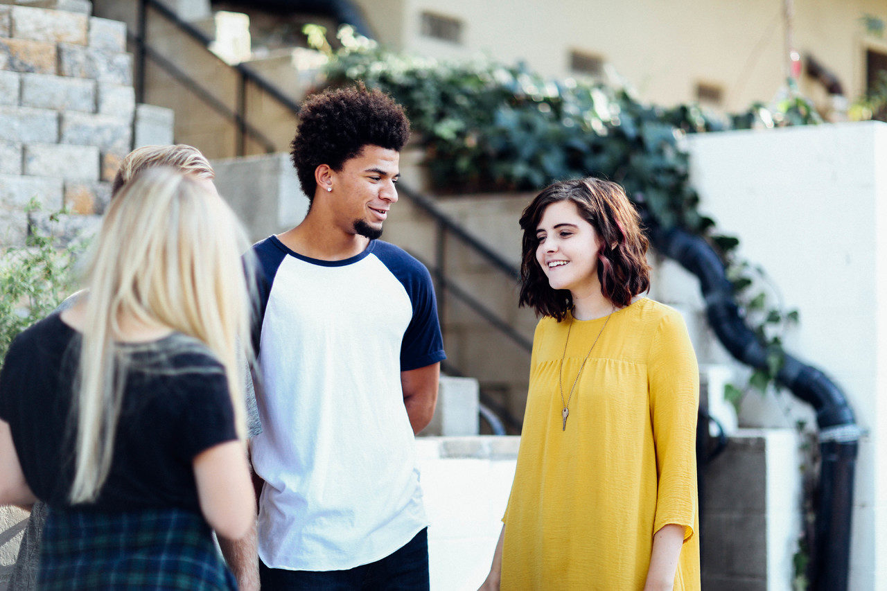 Trois adolescents souriants discutent en extérieur.