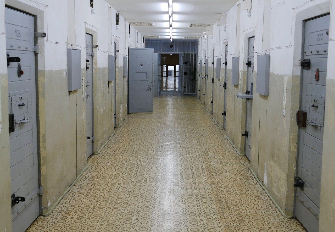 Photo du couloir d'une prison. De chaque côté se trouvent les portes massives des cellules.