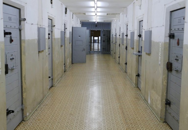 Photo du couloir d'une prison. De chaque côté se trouvent les portes massives des cellules.