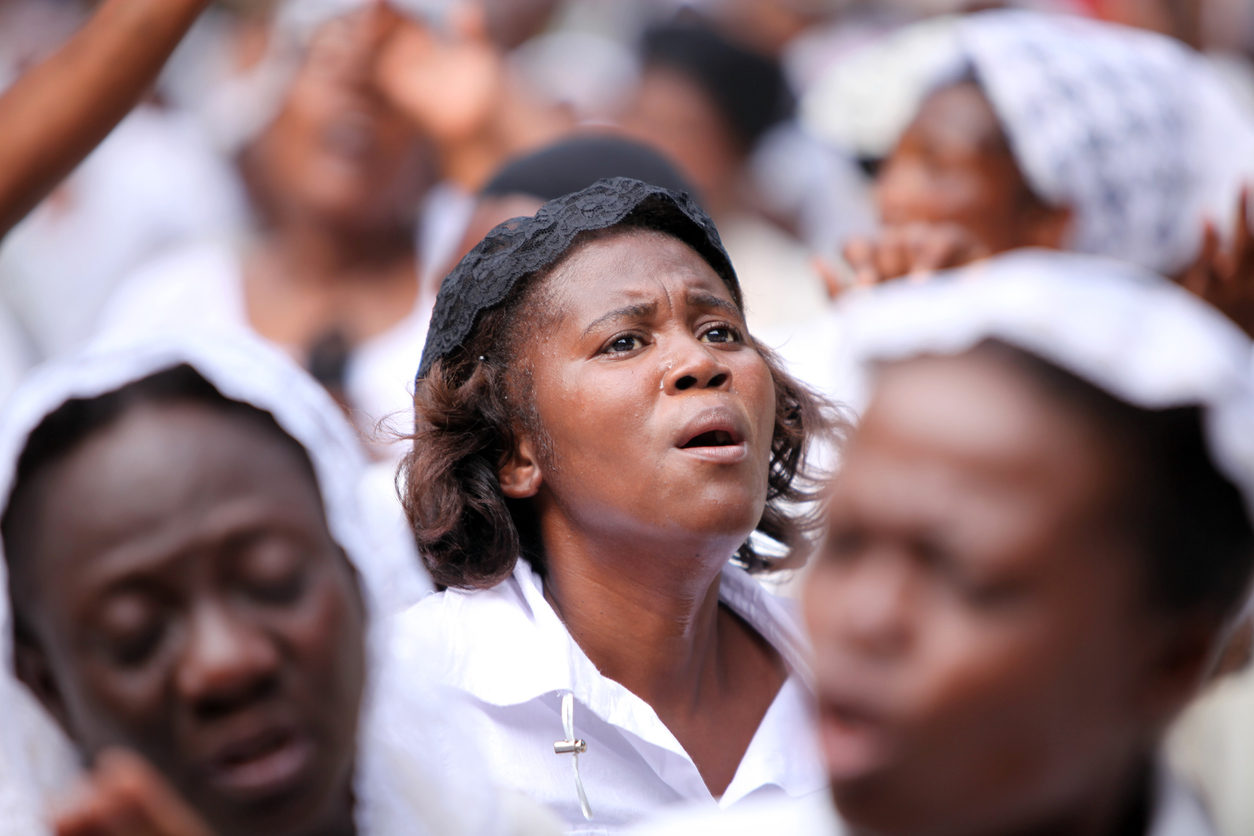 Entourée d'une foule vêtue de blanc, une femme prie