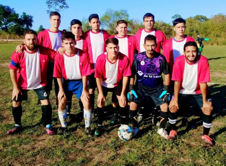 Photo d'une dizaine de footballeurs dans un stade Ils regardent vers l'objectif, et paraissent heureux.