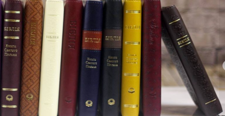 Une rangée de bibles différentes les une des autres, en épaisseur et en couleur. Des caractères cyrilliques apparaissent sur certaines tranches.