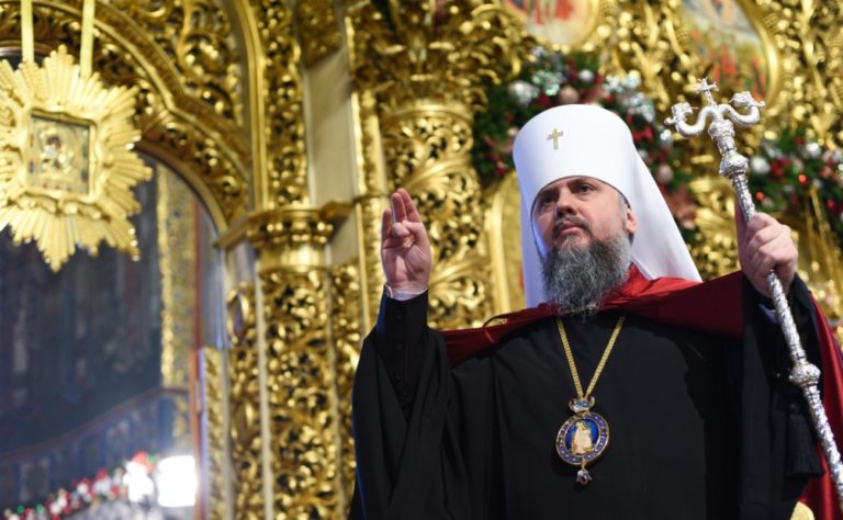 Le métropolite de Kiev Serhiy Doumenko se tient sur une chair dorée et somptueusement ornée. Il fait un signe de bénédiction avec la main. Il tient aussi une crosse en argent.