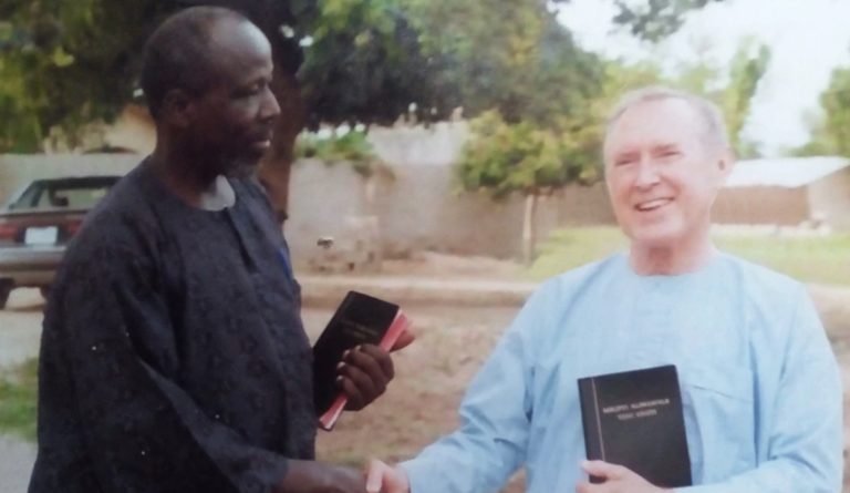 Mark Zira Dlyavaghi et Roger Mohrlang se serrent la main La photo est ancienne. Ils tiennent tous les deux une Bible dans leur main.