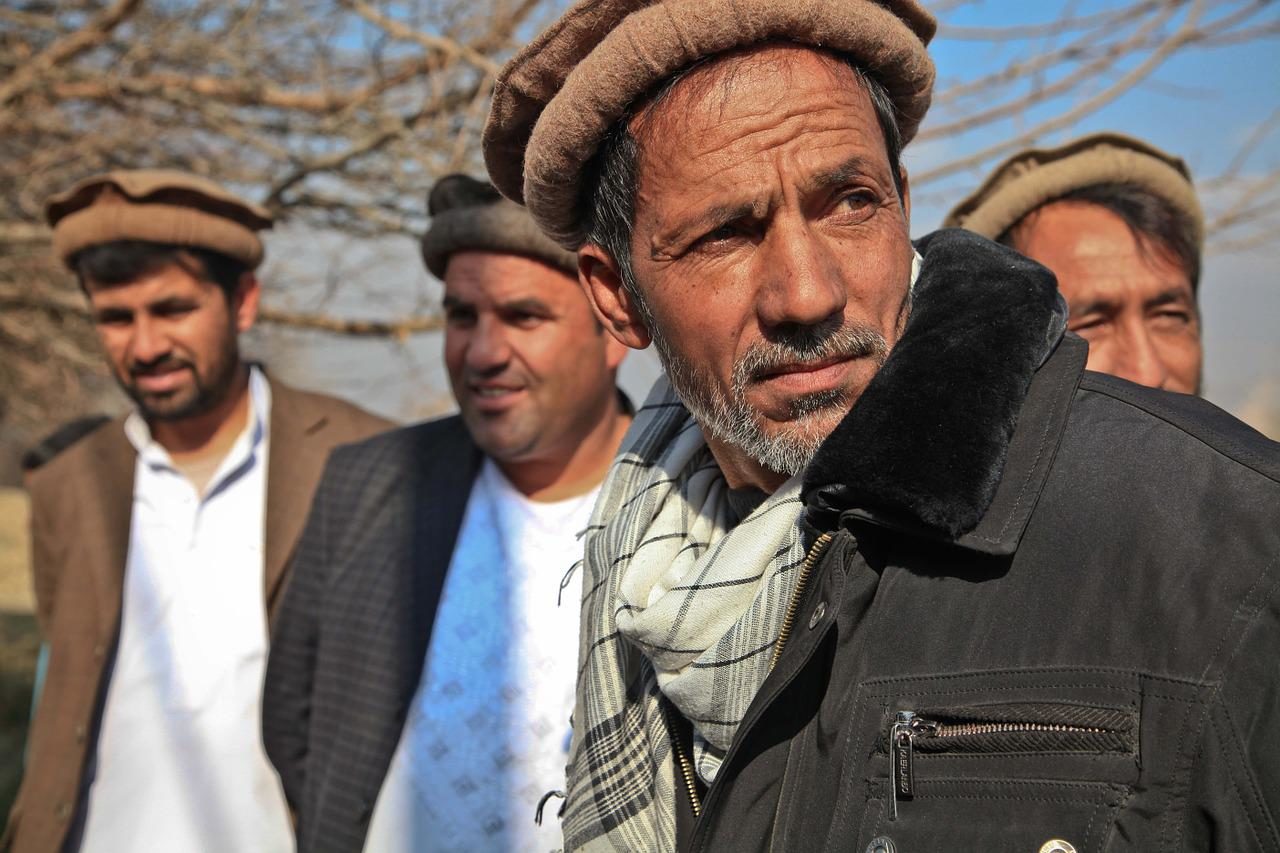 Un groupe d'hommes afghans. Celui qui est au premier plan a l'air méfiant.