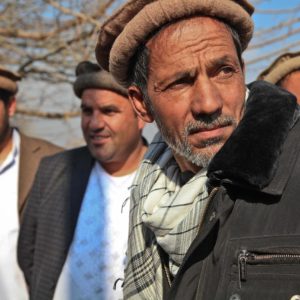 Un groupe d'hommes afghans. Celui qui est au premier plan a l'air méfiant.